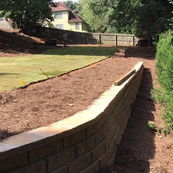 Retaining wall beside lawn with trees.
