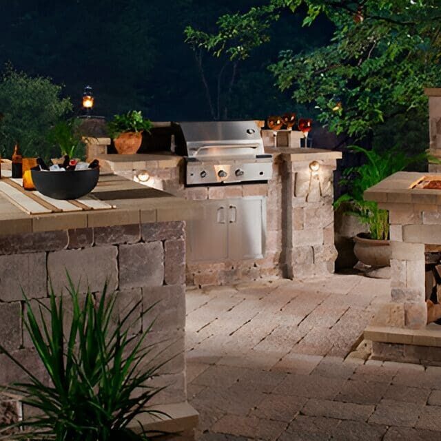 Outdoor kitchen with grill and stone fireplace.